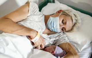 Eine Mutter stillt ihr Baby mit Maske im Bett